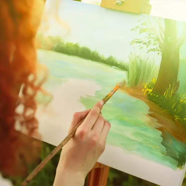 Ragazza di spalle che dipinge un quadro con pennello a olio in un bosco
