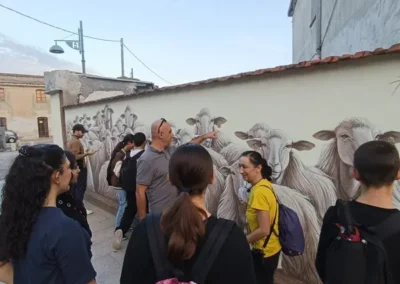 Gruppo di persone riunite davanti a un murales sardo durante la visita a un borgo tipico